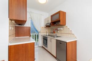 a kitchen with wooden cabinets and a sink at Apartments by the sea Njivice, Krk - 5295 in Njivice +41 photos