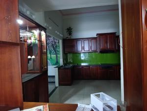 a kitchen with wooden cabinets and a green wall at QN Home in Quy Nhon