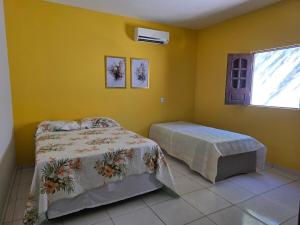 a bedroom with yellow walls and a bed and a window at Mirante in Crato