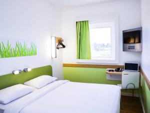 a bedroom with a white bed and a window at ibis budget Campo Grande in Campo Grande
