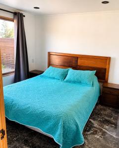 a bedroom with a bed with blue sheets and a window at Cabaña bosquepaz in Algarrobo