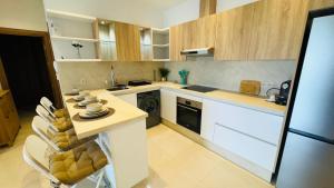 a kitchen with white appliances and wooden cabinets at Les Jardins Bleus Pool - Martil in Martil