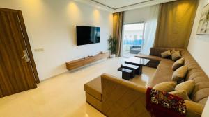 a living room with a couch and a flat screen tv at Les Jardins Bleus Pool - Martil in Martil