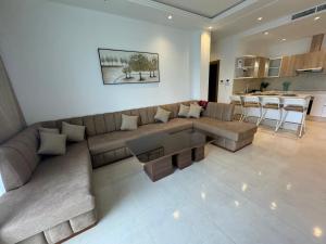 a living room with a large couch and a kitchen at Les Jardins Bleus Pool - Martil in Martil
