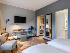 a bedroom with a bed and a desk with a mirror at Mercure Hotel Dortmund Centrum in Dortmund +125 photos