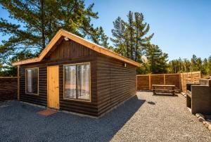 a small wooden cabin with a bench and a fence at Cabaña bosquepaz in Algarrobo