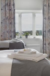 two beds with white towels on them in a room with windows at Værøy Brygge Hotell in Værøy