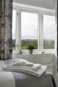 a bedroom with two windows and a bed with a view at Værøy Brygge Hotell in Værøy