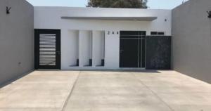 a white house with black doors and a sidewalk at reforma tecoman colima mexico in Tecomán