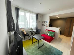 a living room with a red couch and a table at イーエフ千歳駅 in Chitose