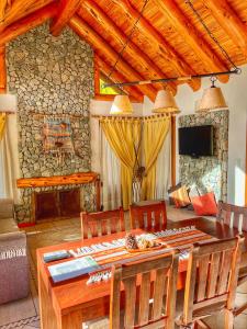 a dining room with a table and a stone fireplace at Paraiso de Montaña in Villa Pehuenia