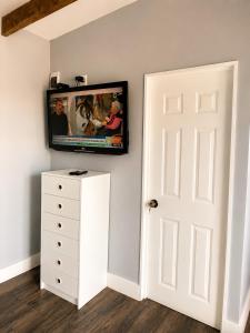 a flat screen tv on a wall above a white dresser at Cabaña bosquepaz in Algarrobo
