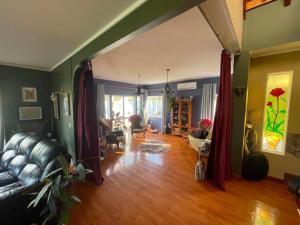 a living room with a black couch and a wooden floor at MoonWillow Manor in Dairy Flat