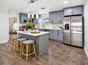 a kitchen with gray cabinets and a large island with bar stools at Tropical Dream - Pool - Firepit - Gazebo in Largo
