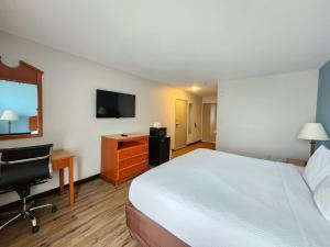a hotel room with a bed and a desk and a television at Days Inn & Suites by Wyndham Thibodaux in Thibodaux