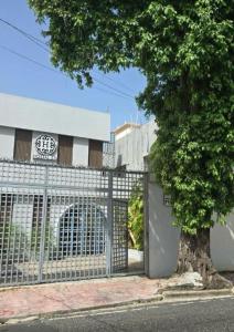 a fence with a tree in front of a building at Hostal 53 Boutique Santo Domingo in Santo Domingo