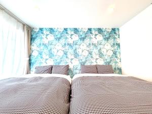two beds in a bedroom with a floral wallpaper at BookHouse in Takasaki