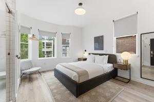 a bedroom with a bed and a chair and windows at The Boylston Hotel Capitol Hill in Seattle