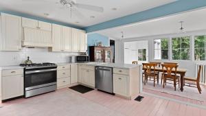 a kitchen with white cabinets and a table with chairs at Victorian On North in Cape May