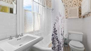 a bathroom with a sink and a toilet and a window at Victorian On North in Cape May +32 photos