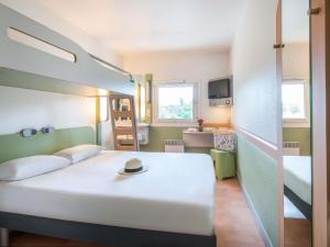 a bedroom with a bed with a hat on it at IBIS Budget Aix en Provence Est Le Canet in Meyreuil +62 photos
