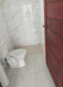 a bathroom with a white toilet and a red door at beach house in Pontal de Coruripe in Coruripe