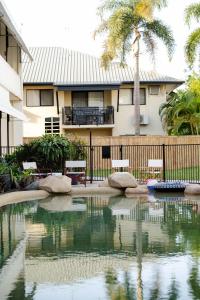 a swimming pool in front of a house with a palm tree at Hotel Allen in Townsville