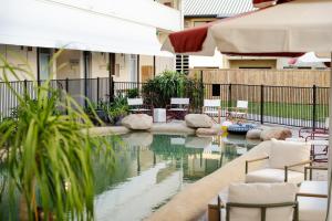 a pool of water with white chairs and tables at Hotel Allen in Townsville