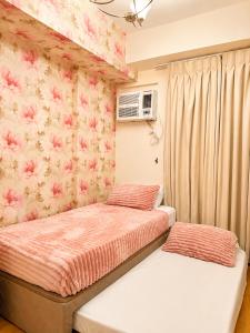 two beds in a bedroom with pink floral wallpaper at Cityscape Suite in Davao City +3 photos