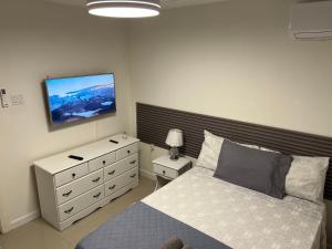 a bedroom with a bed and a dresser and a tv at Mandeville luxury in Mandeville