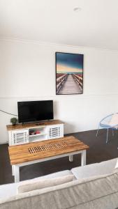 a living room with a tv and a coffee table at Busselton Jetty Chalets in Busselton