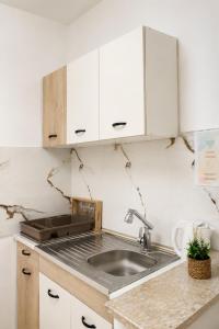 a kitchen with a sink and white cabinets at Apartments Katana in Ulcinj +149 photos