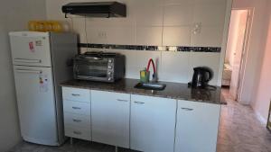 a kitchen with a sink and a microwave and a refrigerator at CASA VERDE 1 depto in Carhué
