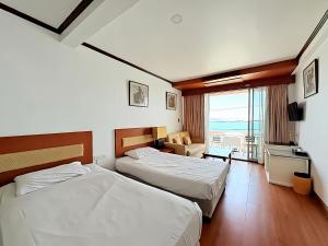 a hotel room with two beds and a balcony at Orchid Hotel and Spa Kalim Bay in Patong Beach