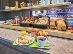 a table with a tray of bread and coffee and pastries at ibis budget Lisieux in Lisieux