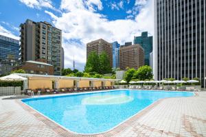 a large pool with chairs and umbrellas in a city at ANA InterContinental Tokyo by IHG in Tokyo