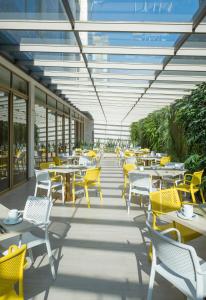 a cafeteria with tables and chairs and yellow chairs at Hotel El Dorado Bogota in Bogotá
