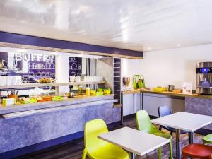 a restaurant with tables and chairs and a counter at ibis budget Brive La Gaillarde in Brive-la-Gaillarde