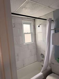 a bathroom with a tub and a shower with a window at Hammock Inn & Suites North Beach Hotel in Seaside Heights