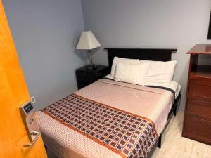 a bedroom with a bed with a lamp and a dresser at Hammock Inn & Suites North Beach Hotel in Seaside Heights