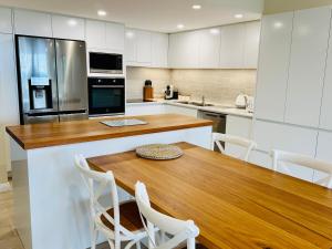 a kitchen with a wooden table and white cabinets at Northpoint Apartments in Port Macquarie