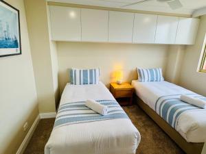two beds in a small room with a night stand at Northpoint Apartments in Port Macquarie