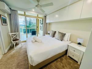 a bedroom with a large white bed and a window at Northpoint Apartments in Port Macquarie