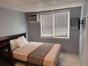 a bedroom with a bed and two windows with blinds at Hammock Inn & Suites North Beach Hotel in Seaside Heights