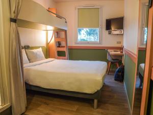 a bedroom with a bed and a desk and a bunk bed at Ibis Budget Bayeux in Bayeux