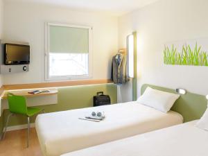 a room with two beds and a desk and a tv at Hotel ibis Budget Laval in Bonchamp-lès-Laval +86 photos
