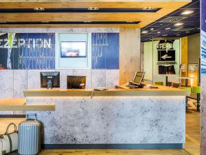a lobby with a reception counter with a suitcase at ibis budget Bordeaux Centre Bastide in Bordeaux