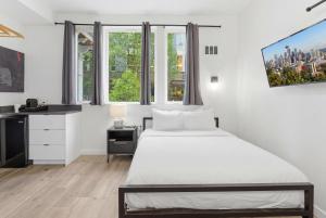 a bedroom with a bed and a desk and windows at The Boylston Hotel Capitol Hill in Seattle