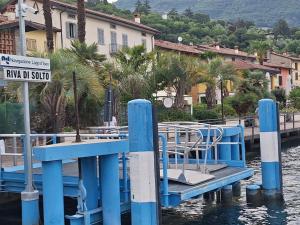 a blue dock with chairs and a street sign on the water at Il Giardinetto in Riva di Solto