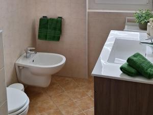 a bathroom with a sink and a toilet and green towels at Il Giardinetto in Riva di Solto